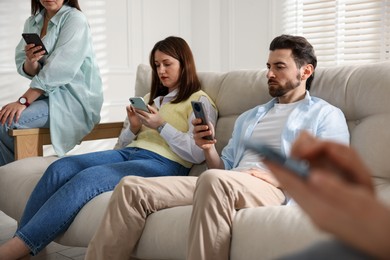 Internet addiction. Group of people with smartphones on sofa indoors