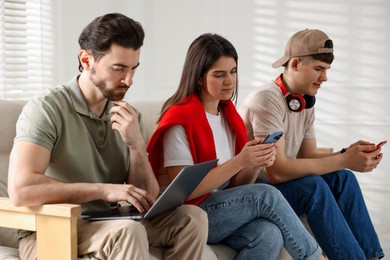 Internet addiction. Group of people with gadgets on sofa indoors