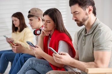 Internet addiction. Group of people with smartphones indoors