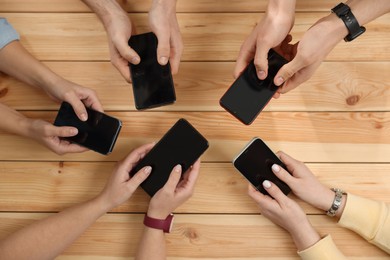 Photo of Internet addiction. People with smartphones at wooden table, top view