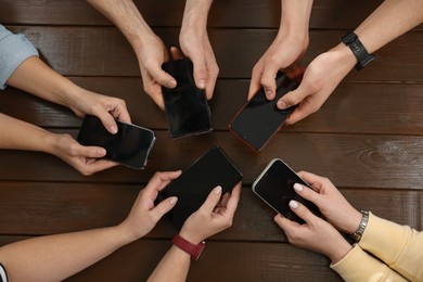 Photo of Internet addiction. People with smartphones at wooden table, top view