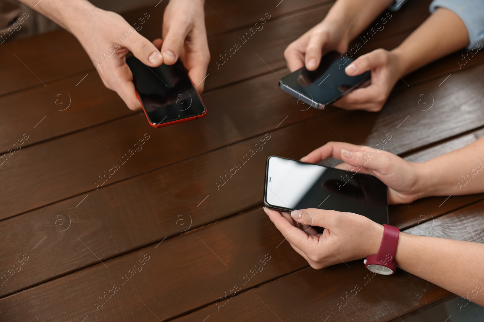 Photo of Internet addiction. People with smartphones at wooden table, closeup