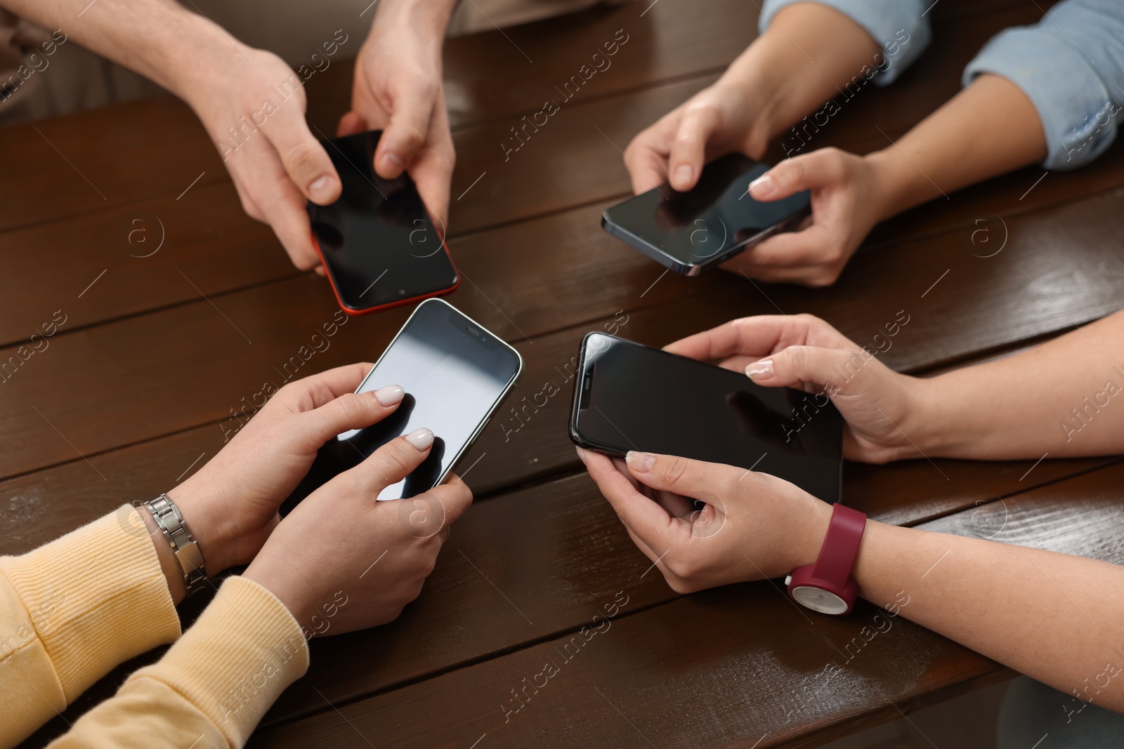 Photo of Internet addiction. People with smartphones at wooden table, closeup