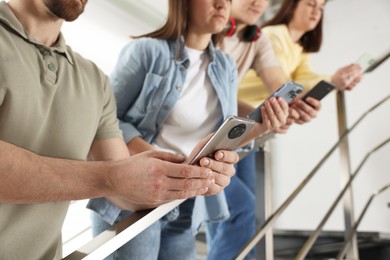 Internet addiction. Group of people with smartphones on stairs indoors, closeup