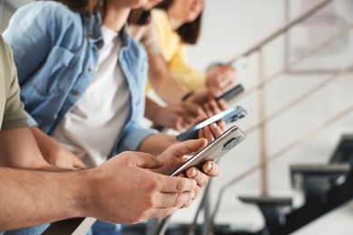 Photo of Internet addiction. Group of people with smartphones on stairs indoors, closeup