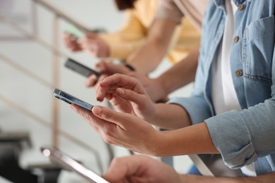 Photo of Internet addiction. Group of people with smartphones on stairs indoors, closeup