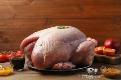 Whole raw turkey with ingredients on wooden table