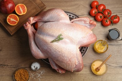 Photo of Whole raw turkey with ingredients on wooden table, flat lay