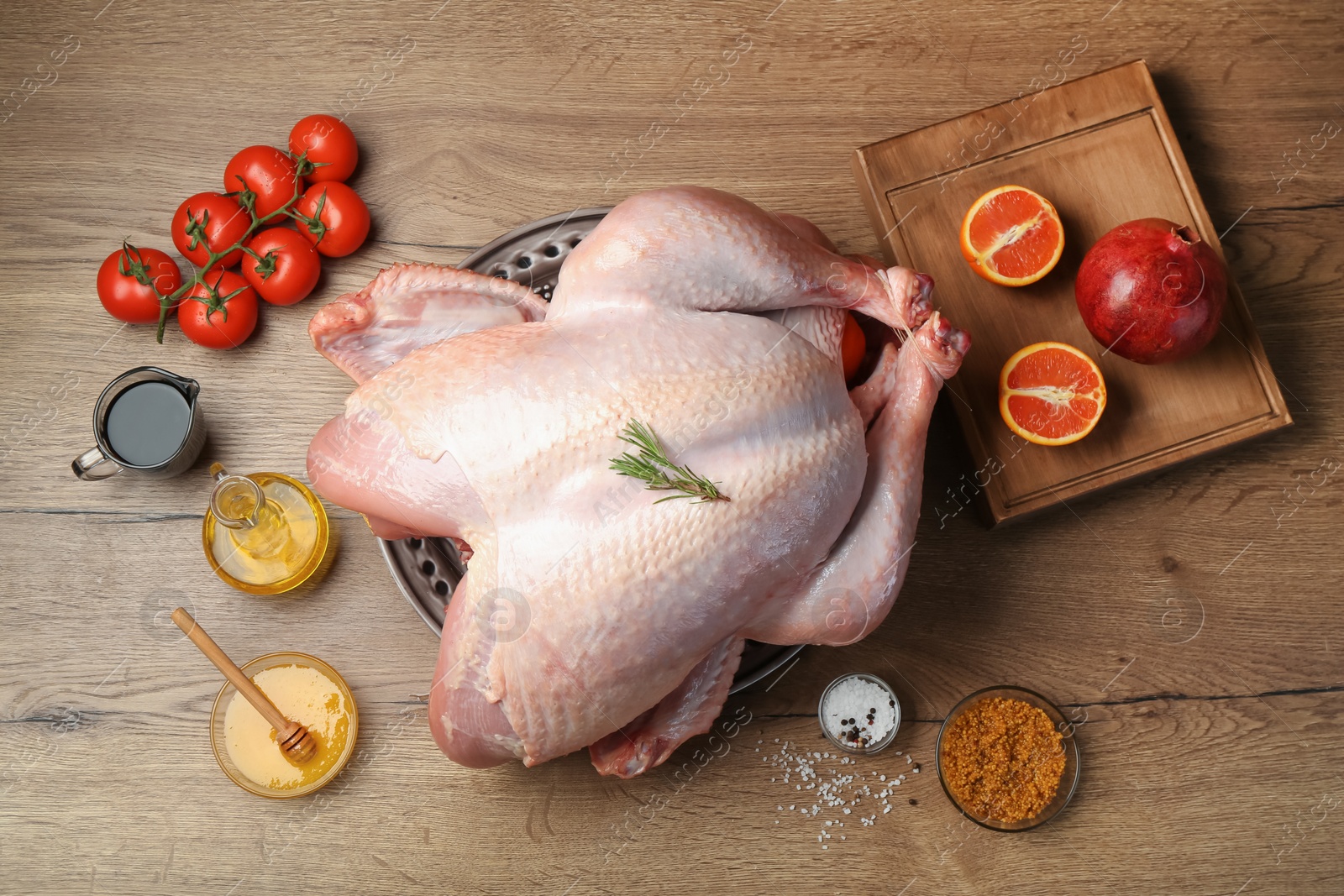 Photo of Whole raw turkey with ingredients on wooden table, flat lay