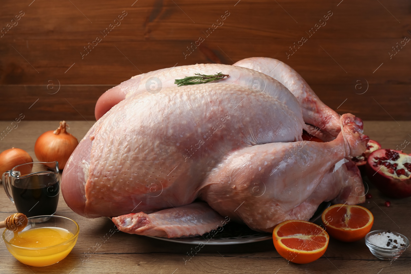 Photo of Whole raw turkey with ingredients on wooden table