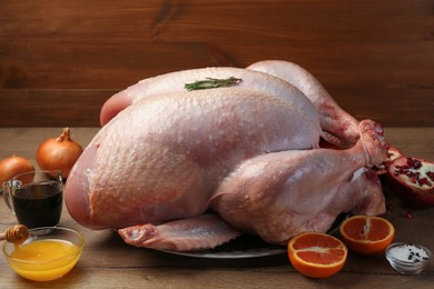 Whole raw turkey with ingredients on wooden table