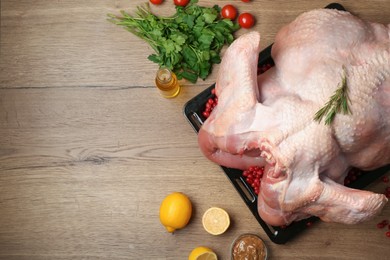 Whole raw turkey with ingredients for marinade on wooden table, flat lay. Space for text