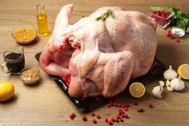 Whole raw turkey with ingredients for marinade on wooden table