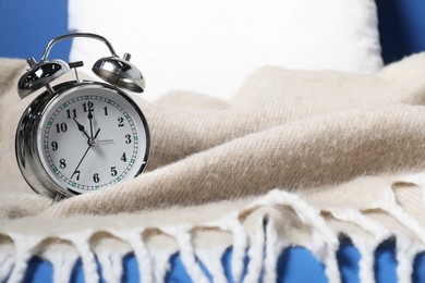 Photo of Alarm clock, pillow and blanket on blue background, closeup. Time for sleeping