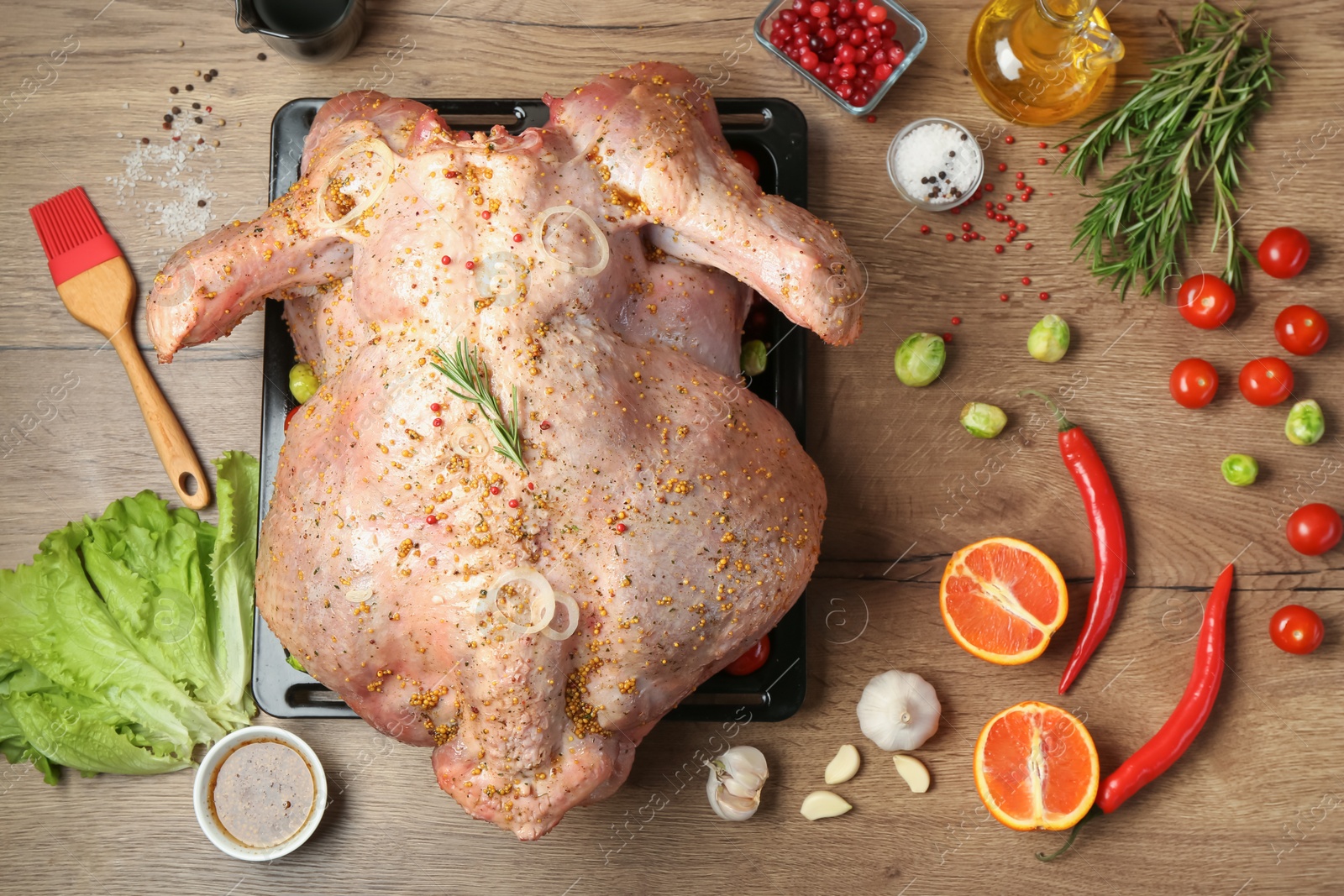 Photo of Whole raw turkey with ingredients for marinade on wooden table, flat lay