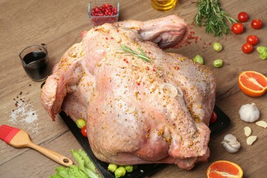 Whole raw turkey with ingredients for marinade on wooden table, closeup