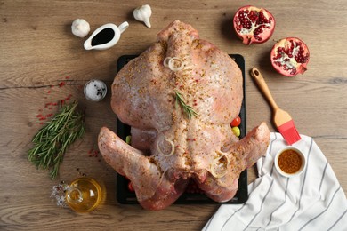 Whole raw turkey with ingredients for marinade on wooden table, flat lay