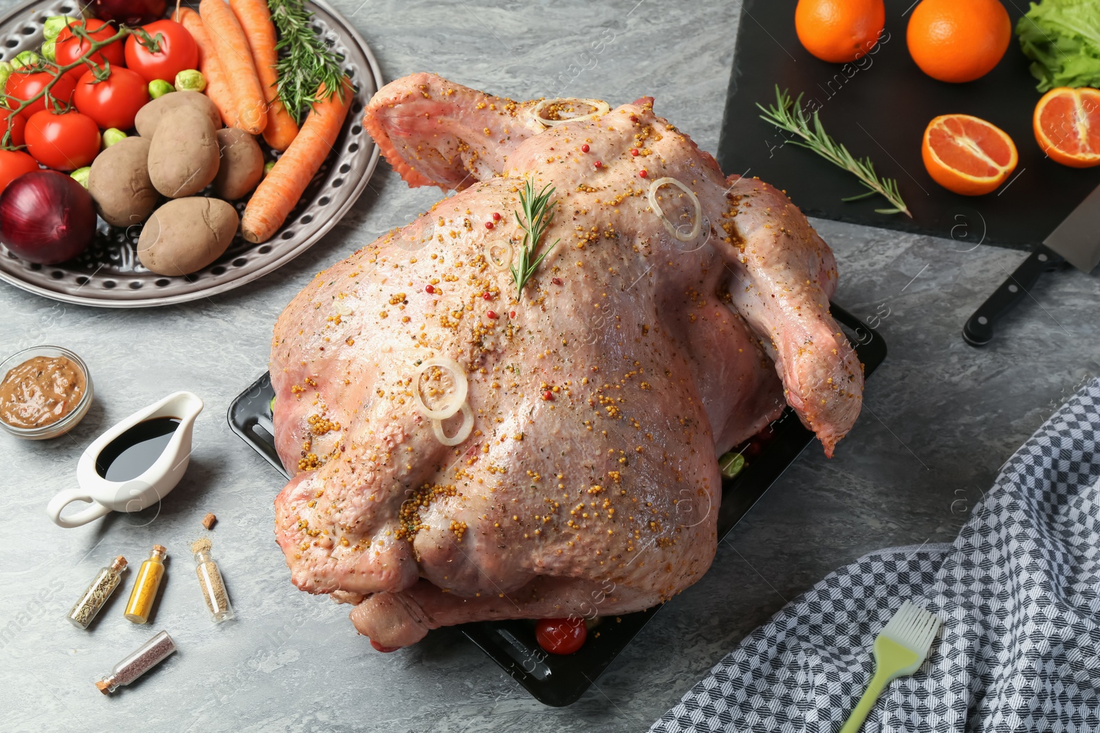 Photo of Whole raw turkey with ingredients for marinade and other products on grey table, above view