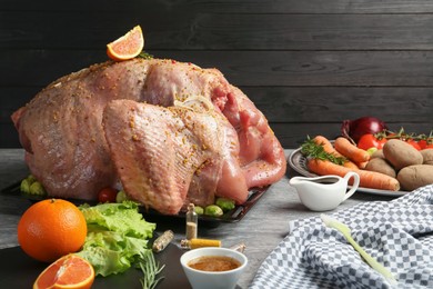 Whole raw turkey with ingredients for marinade and other products on grey table