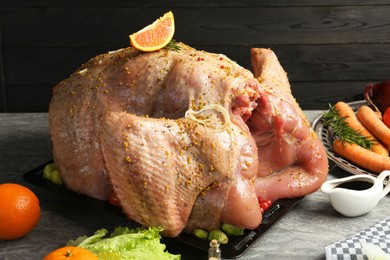 Photo of Whole raw turkey with ingredients for marinade and other products on grey table