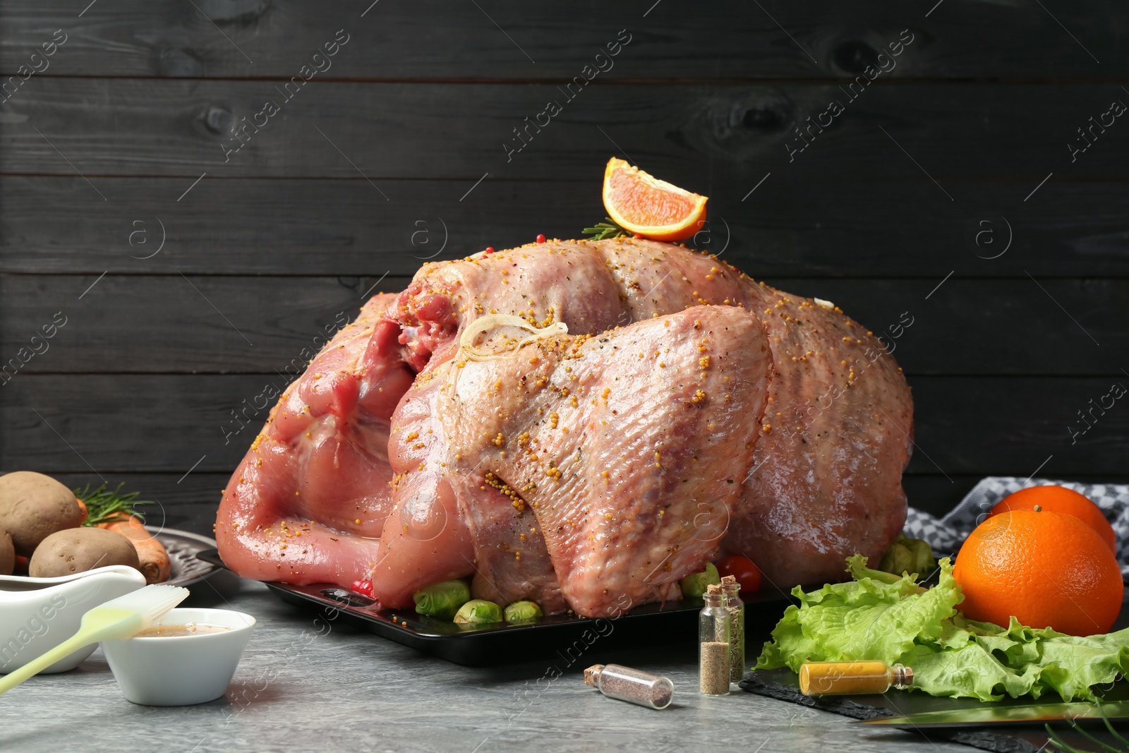 Photo of Whole raw turkey with ingredients for marinade and other products on grey table