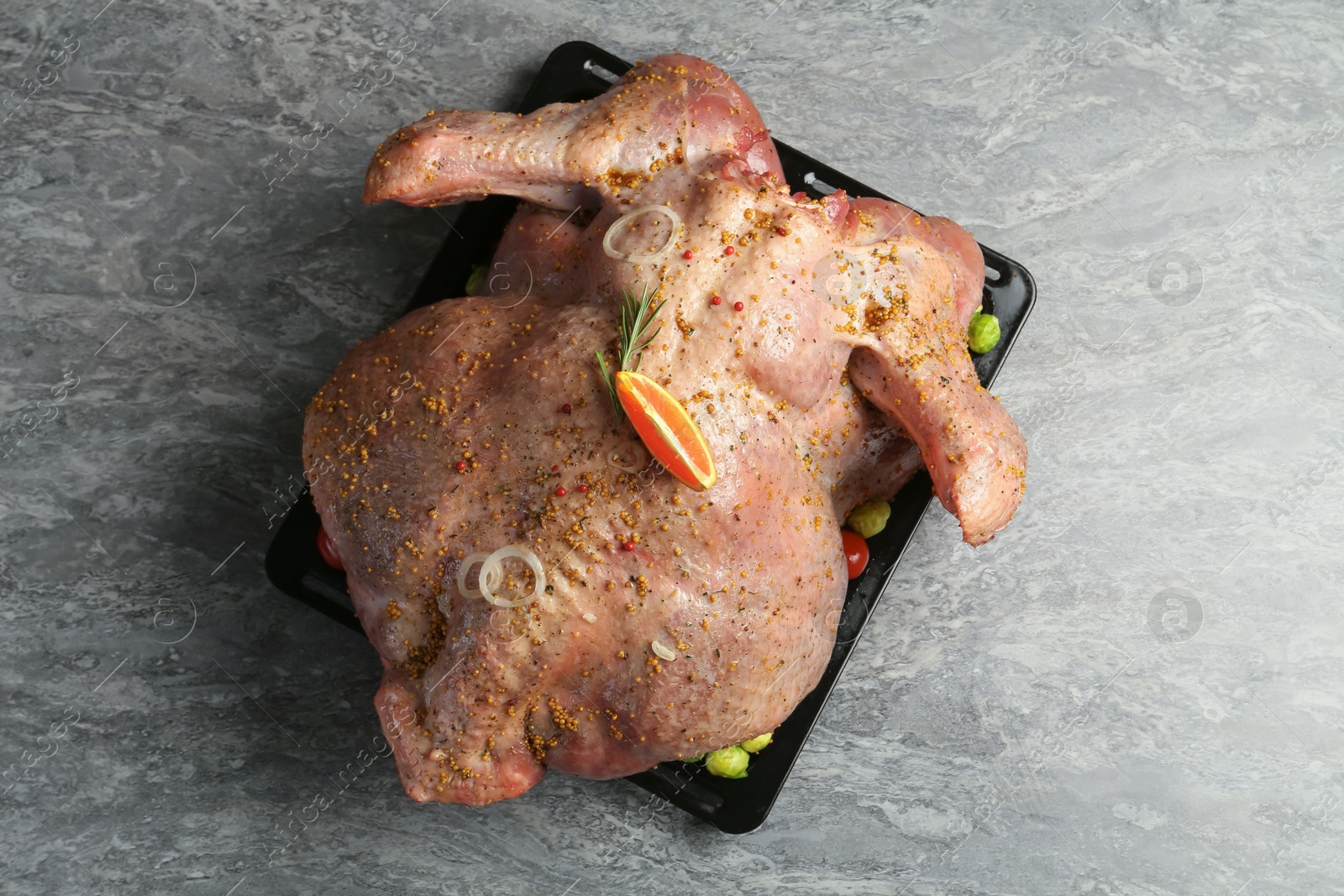 Photo of Whole raw turkey with marinade on grey table, top view