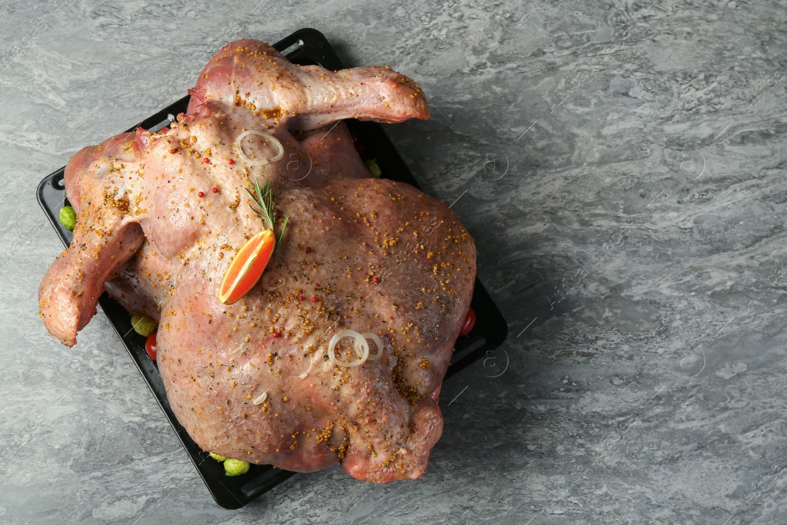 Photo of Whole raw turkey with marinade on grey table, top view. Space for text