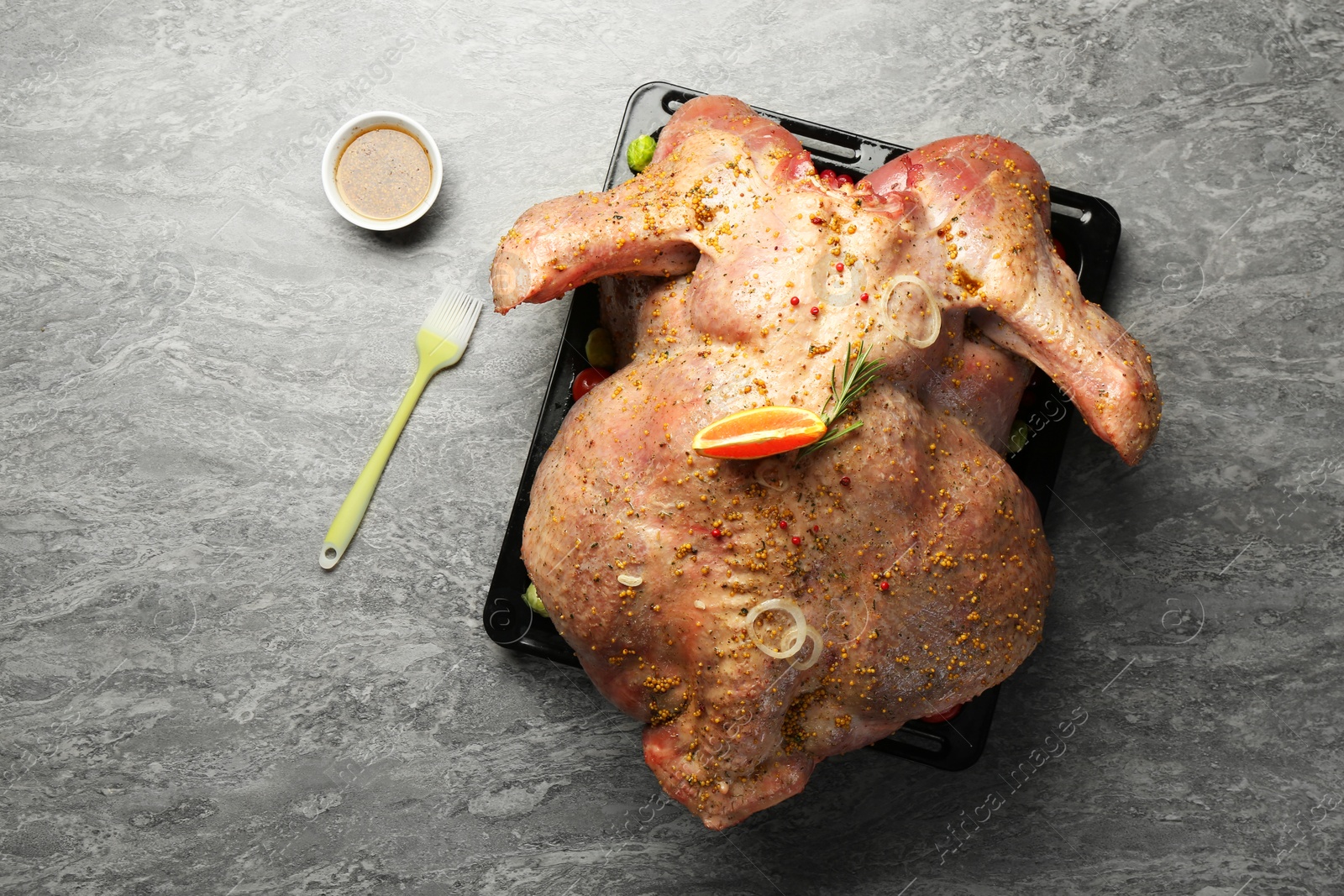 Photo of Whole raw turkey with marinade and basting brush on grey table, flat lay. Space for text