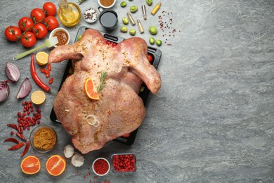 Photo of Whole raw turkey with ingredients for marinade on grey table, flat lay. Space for text