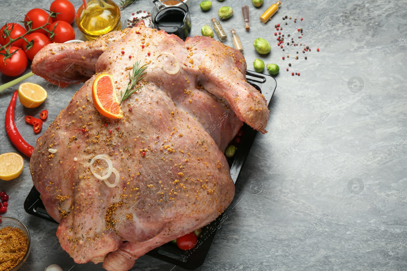 Photo of Whole raw turkey with ingredients for marinade on grey table, closeup. Space for text