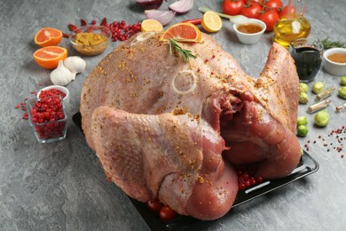 Whole raw turkey with ingredients for marinade on grey table, closeup