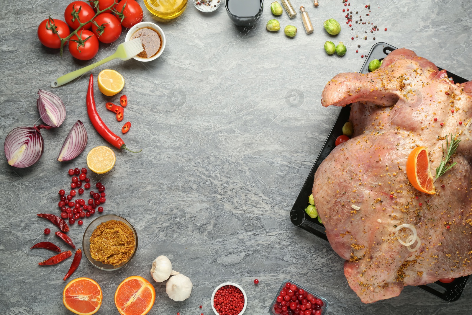 Photo of Frame of whole raw turkey with ingredients for marinade on grey table, flat lay. Space for text