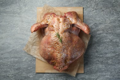 Whole raw turkey with spices on grey table, top view