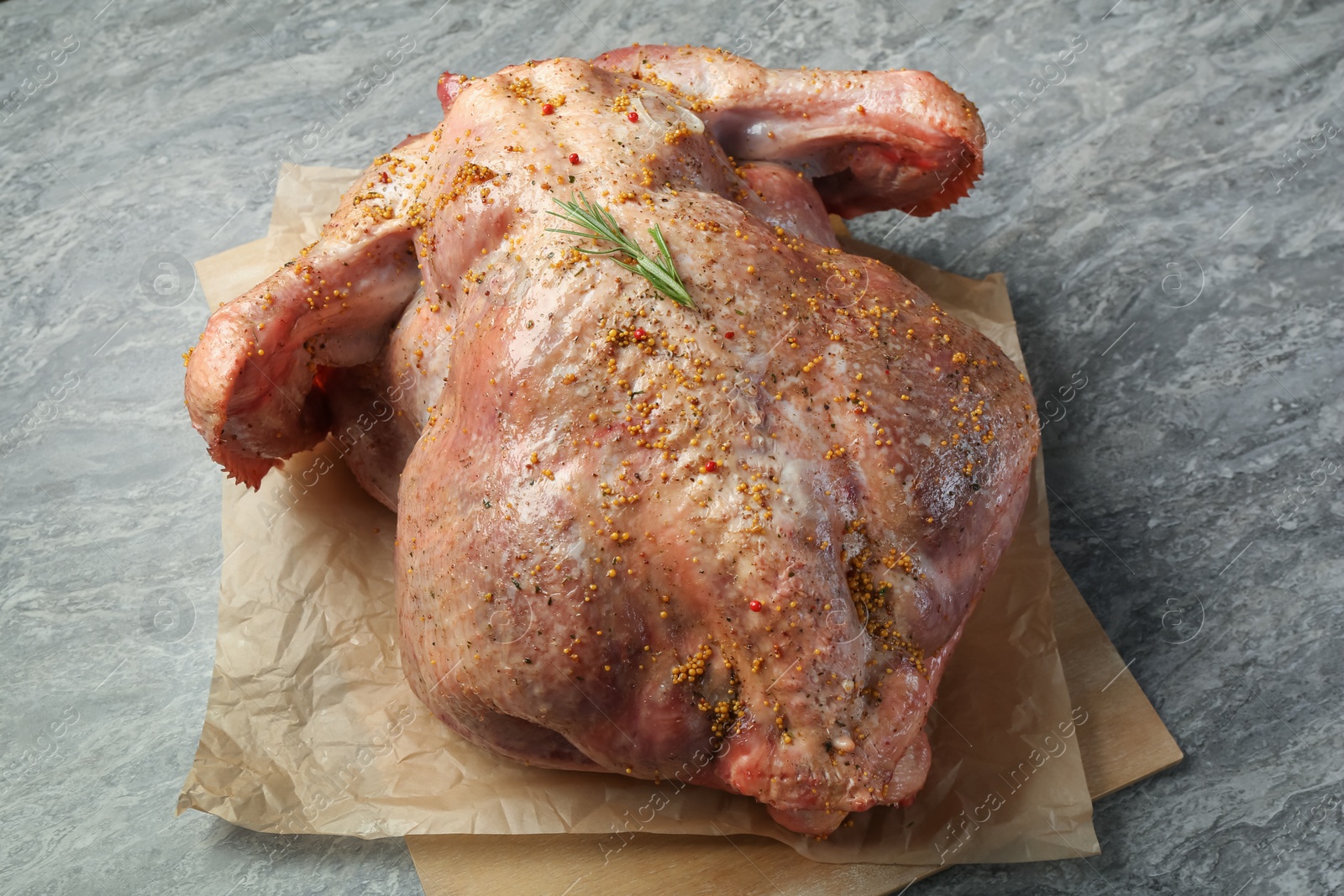 Photo of Whole raw turkey with spices on grey table, closeup