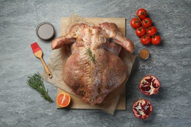 Photo of Whole raw turkey with ingredients for marinade on grey table, flat lay