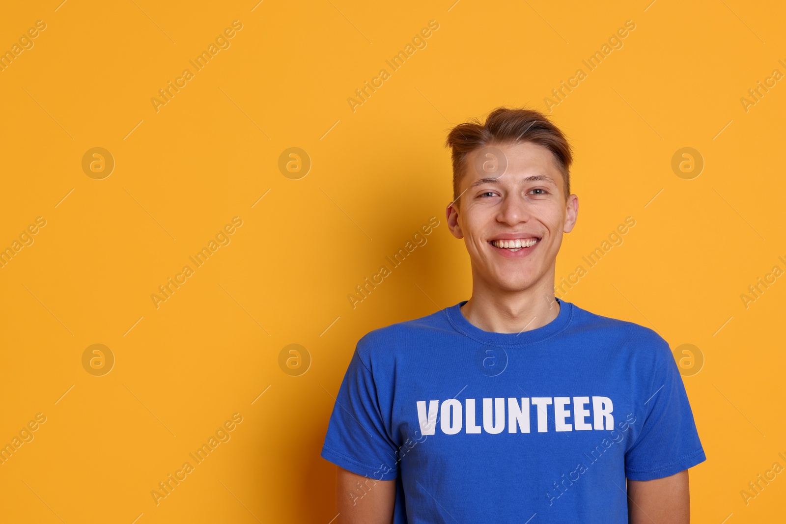 Photo of Portrait of smiling volunteer on orange background. Space for text