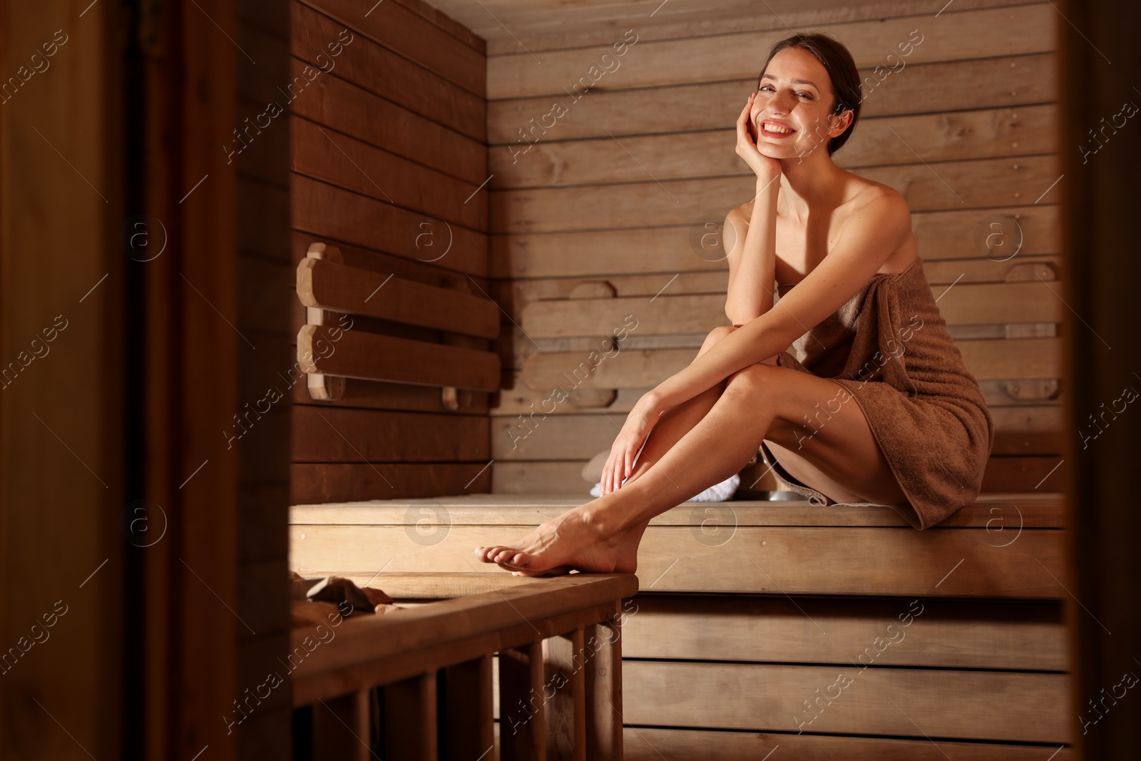 Photo of Smiling woman sitting on bench at sauna. Space for text