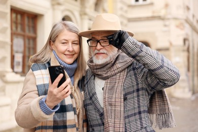 Photo of Lovely elderly couple with smartphone on city street