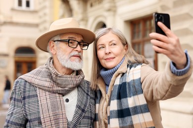 Photo of Lovely elderly couple taking selfie on city street