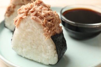 Photo of Tasty onigiri (Japanese rice balls) with tuna and soy sauce on table, closeup