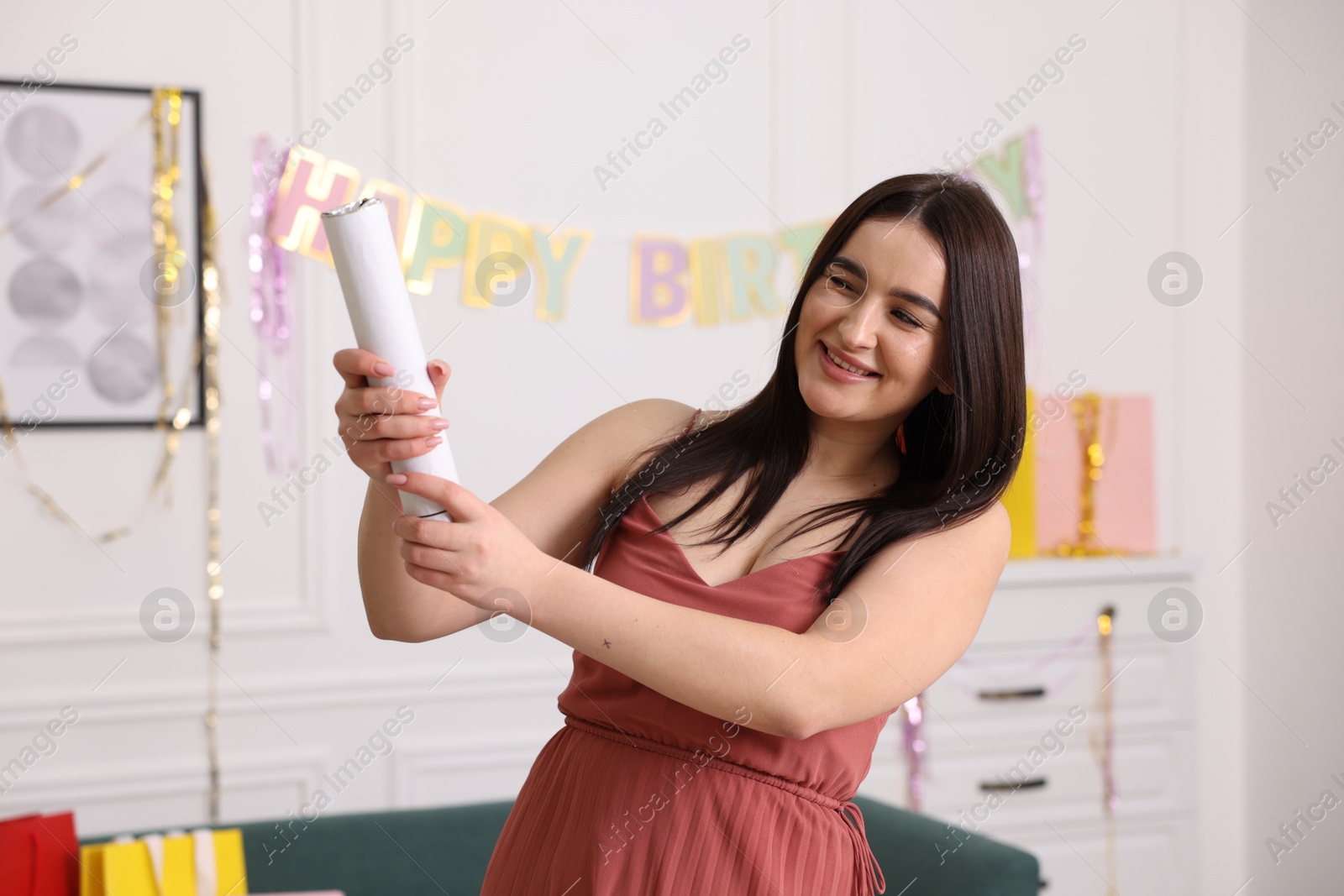 Photo of Happy woman with confetti popper in room decorated for party