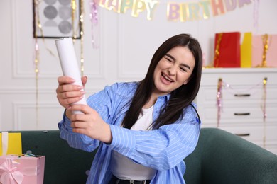 Photo of Happy woman with confetti popper on sofa at home