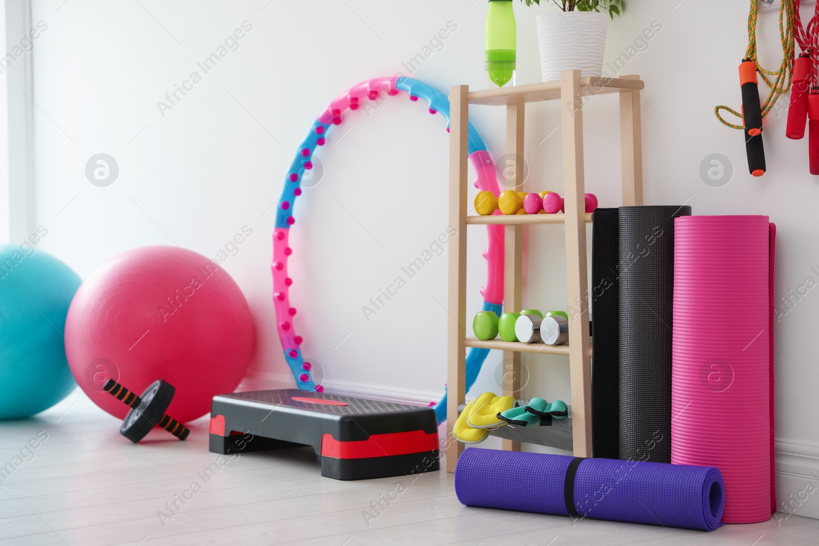 Different fitness equipment near white wall indoors Photo of Different fitness equipment near white wall indoors
