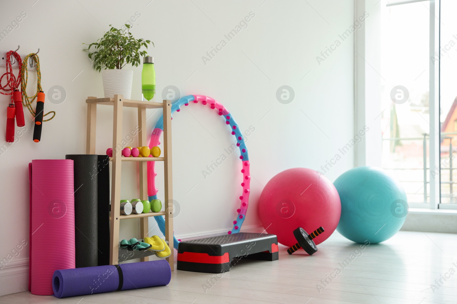 Different fitness equipment near white wall indoors Photo of Different fitness equipment near white wall indoors