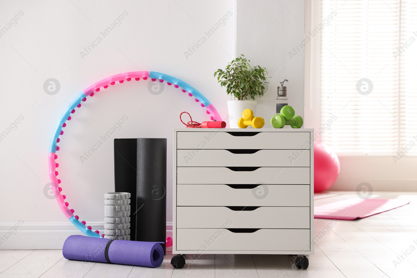 Different fitness equipment and chest of drawers indoors Photo of Different fitness equipment and chest of drawers indoors