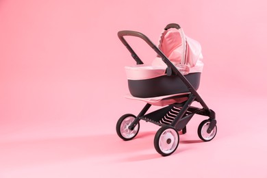 Photo of Stylish doll stroller on pink background, space for text. Kid's toy