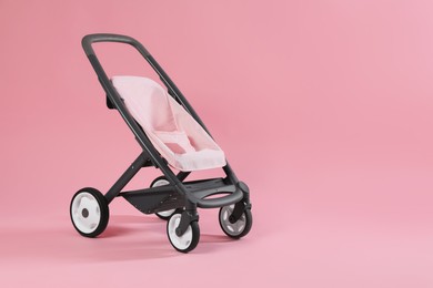 Photo of Stylish doll stroller on pink background, space for text. Kid's toy