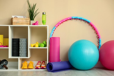 Photo of Different fitness equipment and sneakers near beige wall indoors