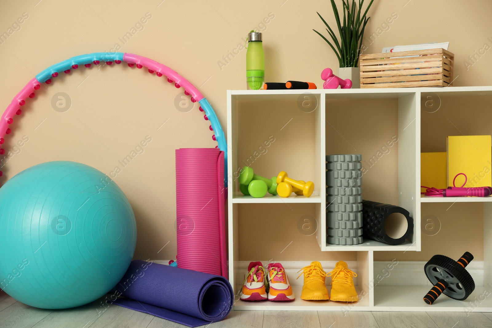 Photo of Different fitness equipment and sneakers near beige wall indoors