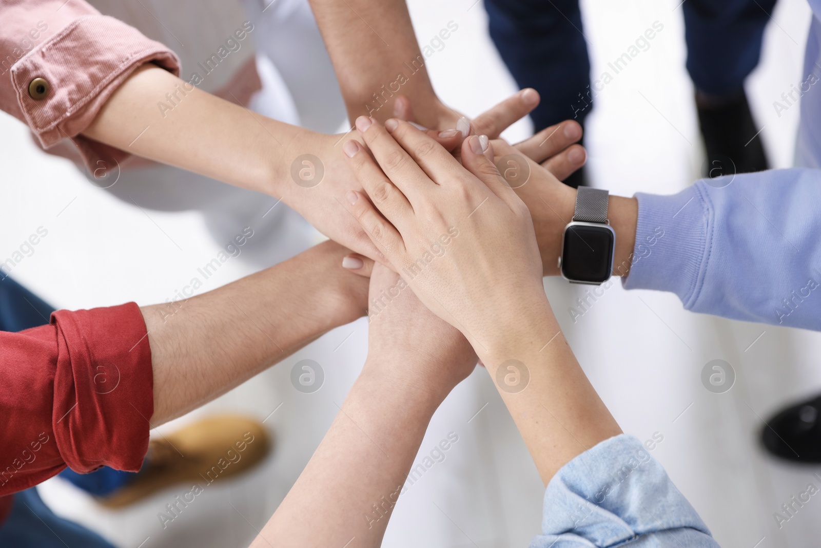 Photo of Unity concept. People holding hands together indoors, above view